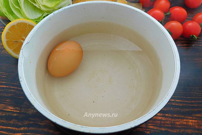 В кастрюле вскипятить воду и опустить сырое куриное яйцо