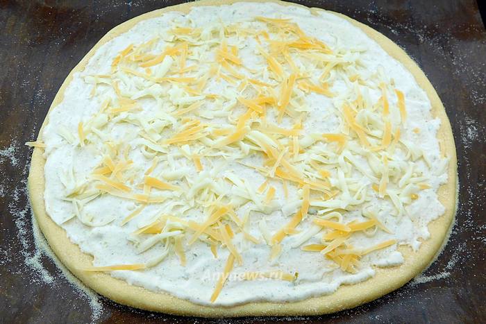 Посыпать пиццу половиной тертого сыра