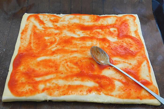 Выложить тесто на противень и смазать томатным кетчупом