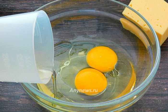 В миску разбить куриные яйца, влить масло
