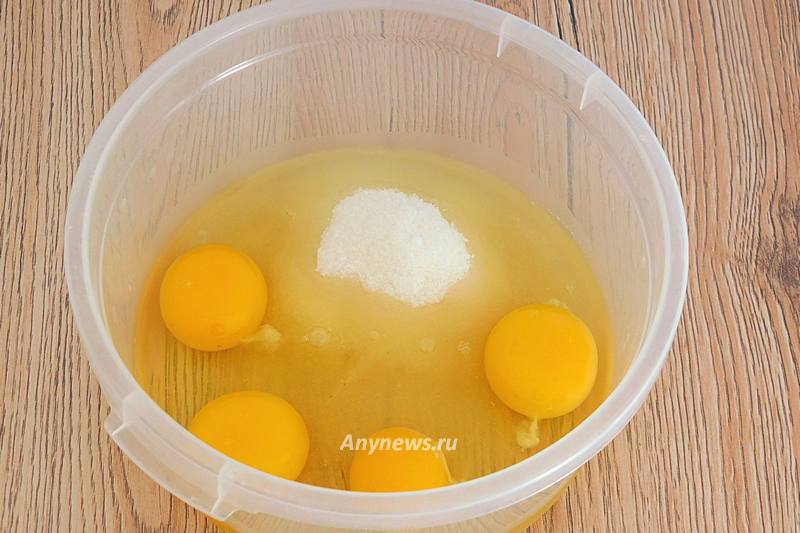В миску всыпать сахар и разбить куриные яйца
