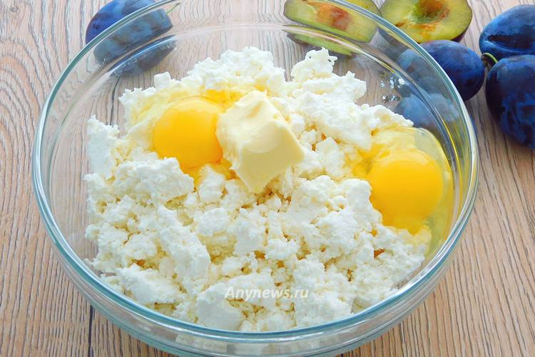 В миску выложить творог, мягкое масло, разбить яйца