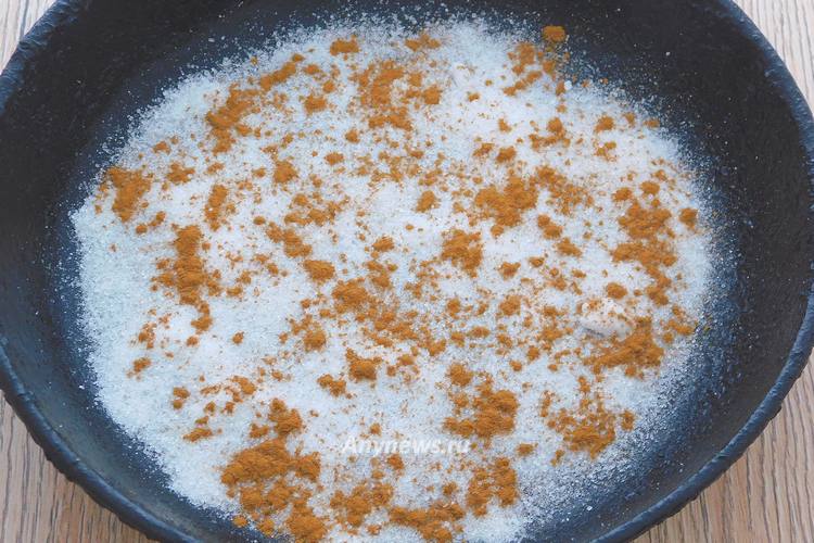 В форму для выпечки насыпать сахар и корицу