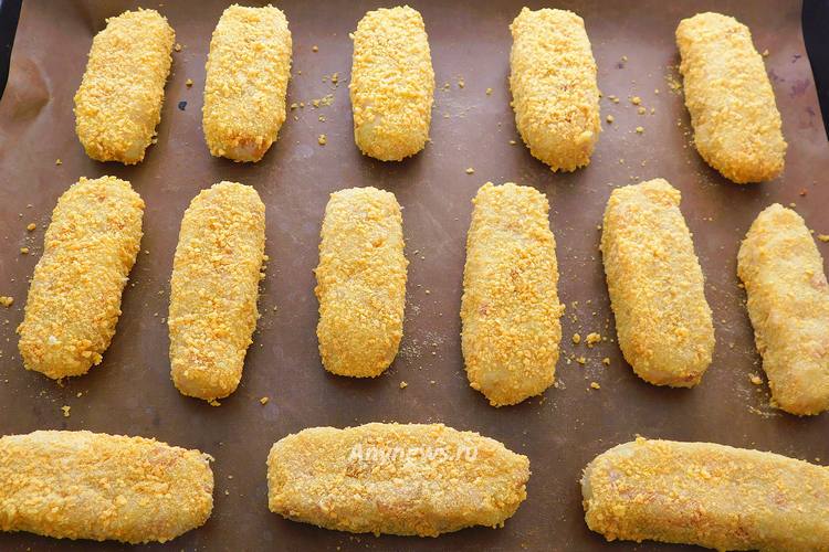 Выложить рыбные палочки в панировке на противень