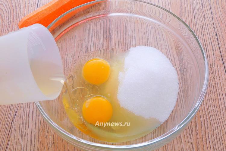 В миску всыпать сахар, разбить куриные яйца, добавить растительное масло