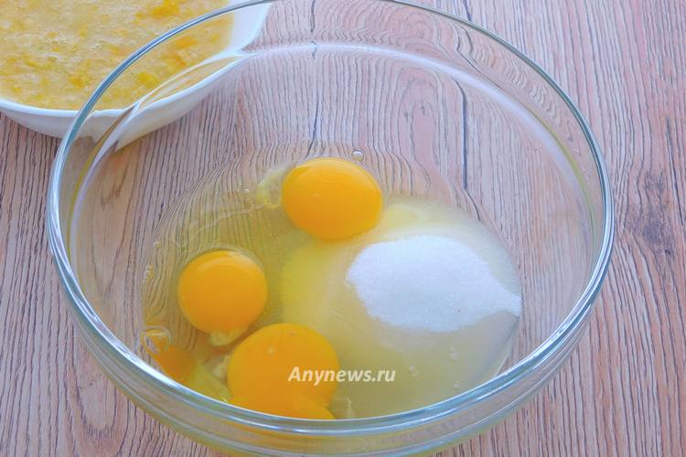 В миску всыпать сахар, разбить куриные яйца
