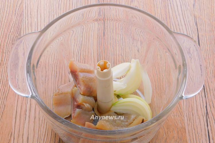 В чашу измельчителя выложить кусочки рыбы и лука