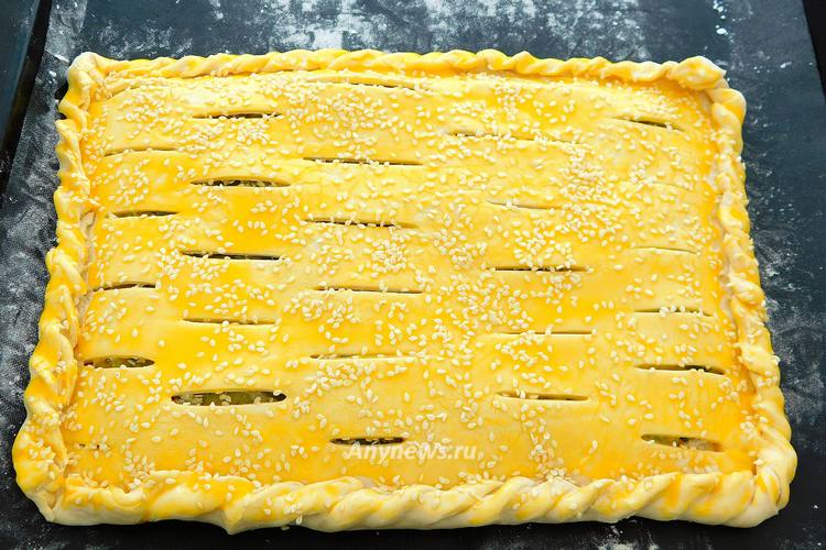 Смазать пирог яичным желтком, посыпать кунжутом